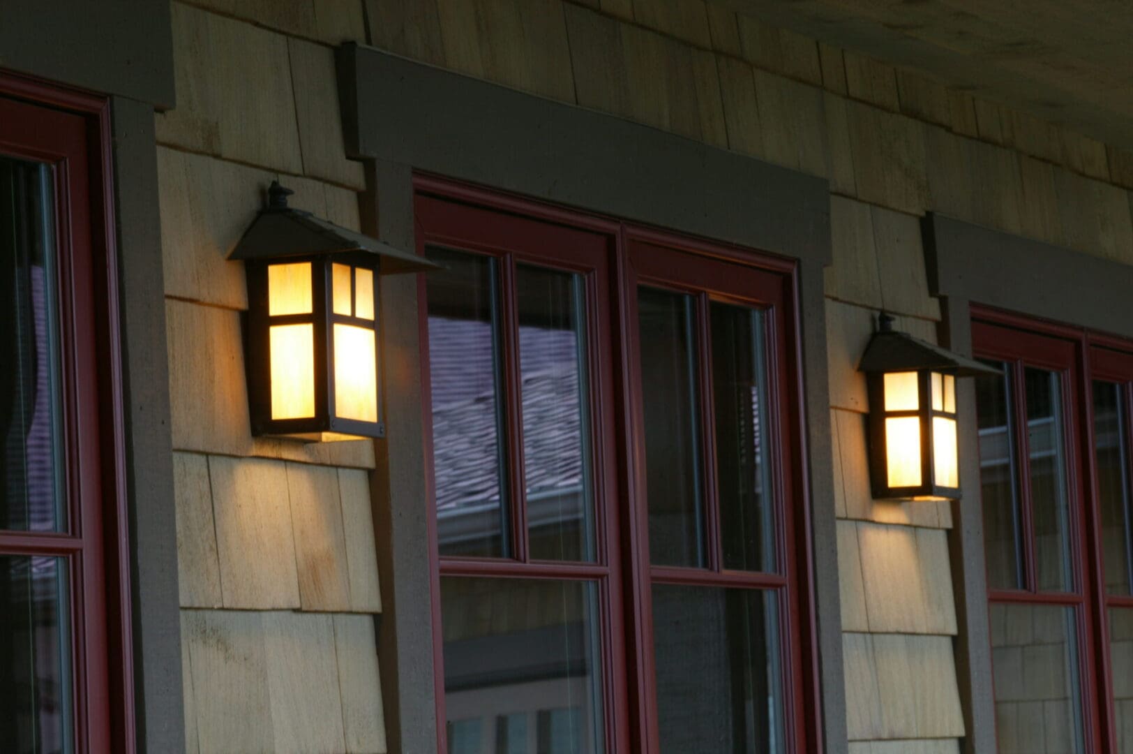 A glass door with a red border flanked by lamps on either side of the door